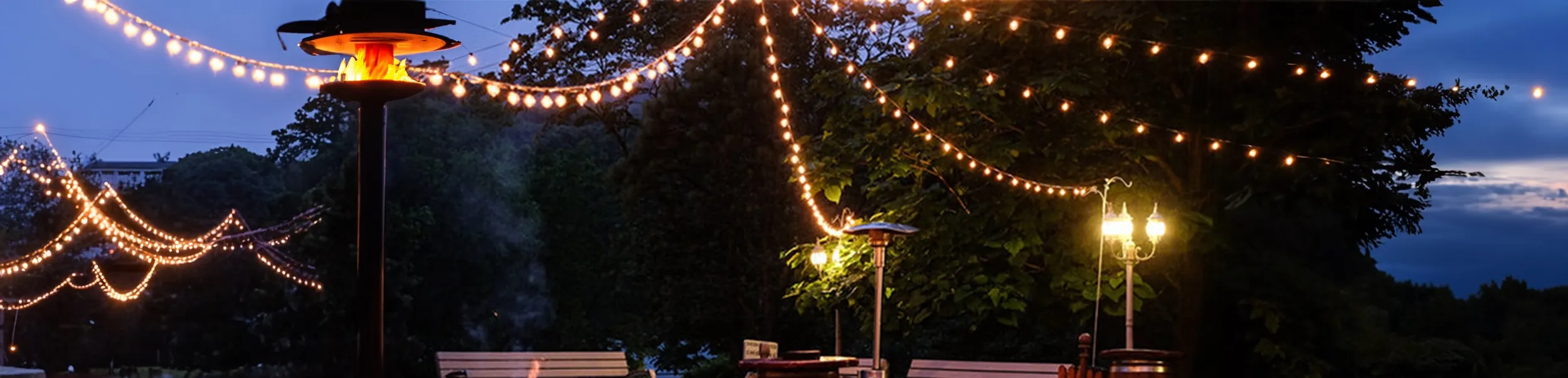 A dense canopy of warm festoon lighting rigged over an outdoor seating area at dusk