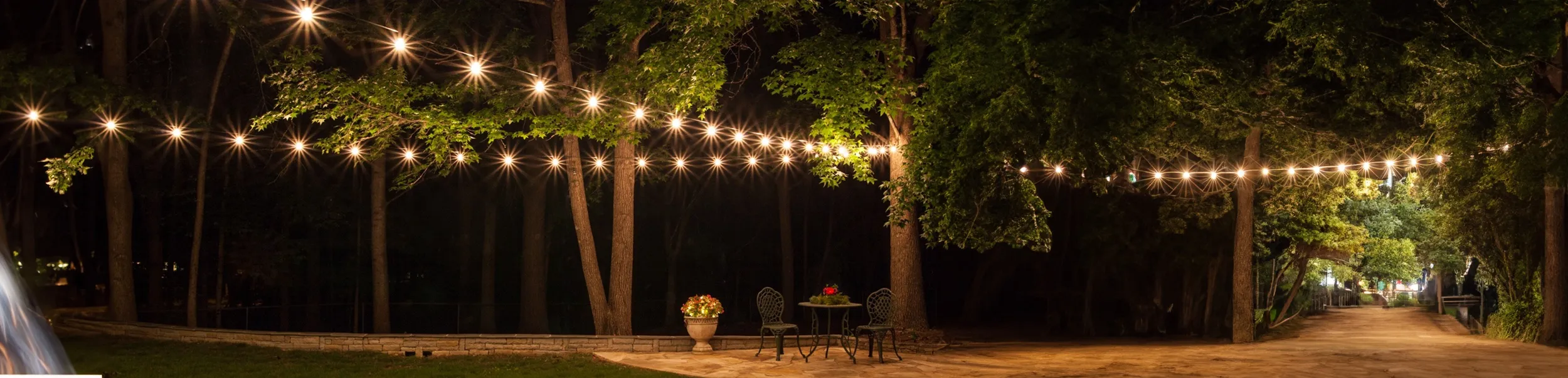 A single festoon span rigged on poles over a garden courtyard at night